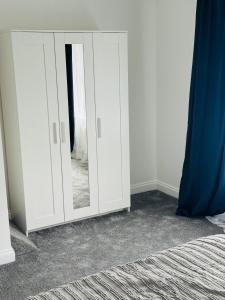 a white cabinet with a mirror in a bedroom at City Dreams in Croydon