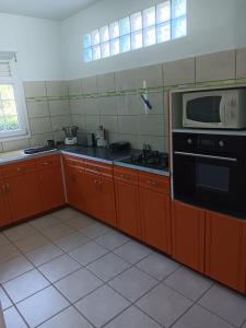 een keuken met oranje kasten, een magnetron en een fornuis bij Pagerie bas de villa in Les Trois-Îlets