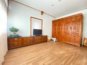 a living room with a large wooden cabinet and a television at Stay Sayu Hanok in Gyeongju