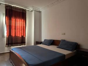 1 dormitorio con 1 cama y una ventana con cortinas rojas en Appart meublé haut standing, WIFI, TV - Yaoundé, Omnisports, en Yaoundé