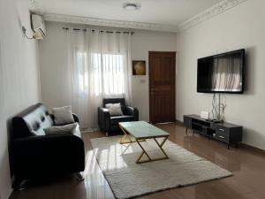 sala de estar con sofá, mesa y TV en Appart meublé haut standing, WIFI, TV - Yaoundé, Omnisports en Yaundé