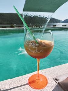 a glass of wine sitting next to a swimming pool at Pensiunea Sunshine in Eşelniţa
