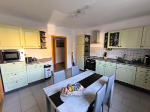 a kitchen with white cabinets and a table with a bowl on it at Ferienwohnung "Spatzennest" in Pirna