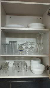 un estante lleno de vasos, platos y tazones en studio 1 étoile paisible,4 couchages,jardin privé en Les Adrets de l'Esterel