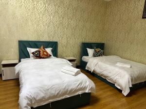 1 dormitorio con 2 camas con edredones blancos en 阿拉木图陶萨马勒民宿, en Almaty