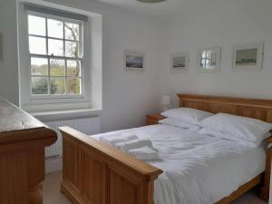 a bedroom with a bed with white sheets and a window at The Captain's House Charlestown St Austell in Charlestown