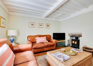 a living room with leather furniture and a fireplace at Wyvern Cottage in Swanage