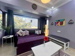 uma sala de estar com um sofá roxo e uma janela em Newton Villa, A Hidden Gem with a Pvt Terrace in the Heart of Bandra by Connekt Homes em Mumbai