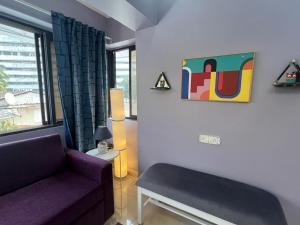 a living room with a purple couch and a painting at Newton Villa, A Hidden Gem with a Pvt Terrace in the Heart of Bandra by Connekt Homes in Mumbai