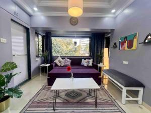 uma sala de estar com um sofá roxo e uma mesa em Newton Villa, A Hidden Gem with a Pvt Terrace in the Heart of Bandra by Connekt Homes em Mumbai