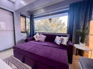 a purple bed in a room with a large window at Newton Villa, A Hidden Gem with a Pvt Terrace in the Heart of Bandra by Connekt Homes in Mumbai