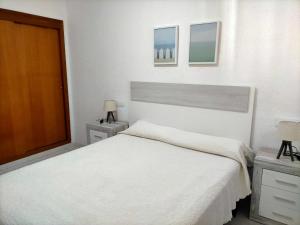 1 dormitorio blanco con 1 cama grande y 2 mesitas de noche en Apartamento céntrico en primera linea de playa, en Peñíscola