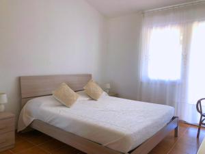 Schlafzimmer mit einem Bett mit weißer Bettwäsche und einem Fenster in der Unterkunft Casa Rita in Costa Paradiso