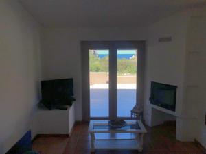 ein Wohnzimmer mit einem Glastisch und einem Fenster in der Unterkunft Casa Rita in Costa Paradiso