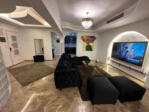 een woonkamer met zwart meubilair en een flatscreen-tv bij Modern 1-Bedroom apartment in Zamalek in Caïro