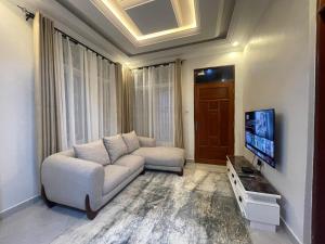 Little Sanctuary 1 Bedroom Apartment في دار السلام: غرفة معيشة مع أريكة وتلفزيون بشاشة مسطحة