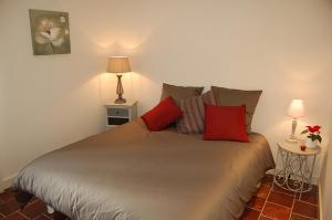 ein Schlafzimmer mit einem großen Bett mit roten Kissen in der Unterkunft Gîtes du Vieux Tilleul, l'Ecurie. in Marseillette
