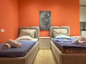 two beds in a room with orange walls at Tirana Center Apartaments in Tirana