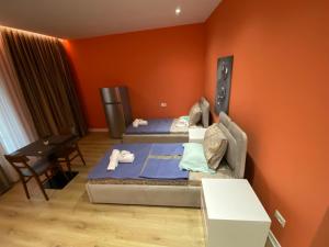 two beds in a room with an orange wall at Tirana Center Apartaments in Tirana