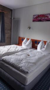 1 cama grande con sábanas blancas y almohadas. en Kloster Cornberg, 