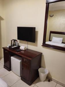 a room with a desk with a television and a bed at Liberty Avenue Hotel in Doha