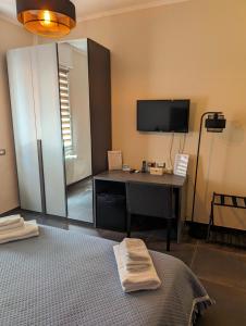 a room with a bed and a desk and a tv at Benedict Rooms in Bologna