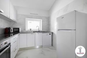 een witte keuken met een wastafel en een koelkast bij Charming Villa Sam in Albufeira