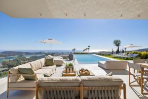 een woonkamer met een bank en een zwembad bij Exclusive VILLA IMAGINE MARBELLA breathtaking panoramic sea views heated infinity pool in Benahavís