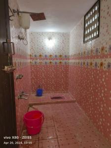 a bathroom with a red tiled shower with a bucket at Sai Home Stay in Tiruvannāmalai