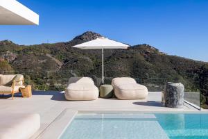 een zwembad met twee stoelen en een parasol bij Exclusive VILLA IMAGINE MARBELLA breathtaking panoramic sea views heated infinity pool in Benahavís