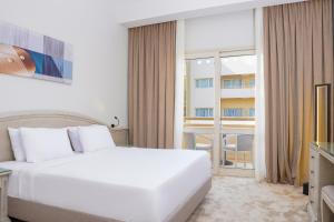 a white bedroom with a large bed and a window at Triumph Plaza Hotel in Cairo