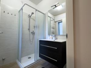 uma casa de banho com uma cabina de duche em vidro com um lavatório e um espelho. em [Venezia-Mestre] Design Apartment Bros#1 em Veneza