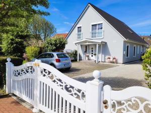 a white picket fence in front of a white house at Lilly & Fine in Zingst