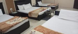 un grupo de 3 camas en una habitación en silk.hotel en Faisalabad