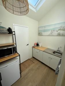 a kitchen with a sink and a microwave at Bed & Beach Noordwijk - free parking and close to beach! in Noordwijk aan Zee