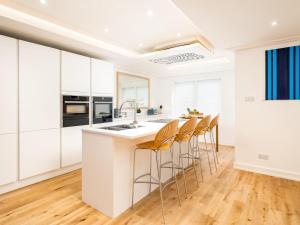 a kitchen with white cabinets and a kitchen island with stools at Lux Light Spacious- Chilterns Pass the Keys in Amersham