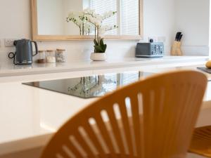 a kitchen counter with a chair and flowers on it at Lux Light Spacious- Chilterns Pass the Keys in Amersham