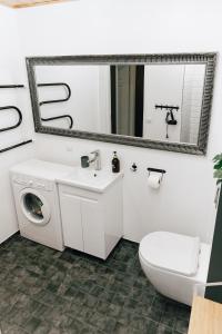 ein weißes Bad mit einer Waschmaschine und einem Spiegel in der Unterkunft Gonsiori Apartment in Tallinn