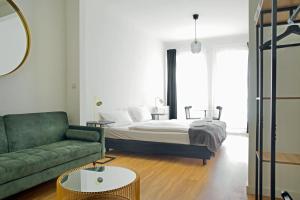 1 dormitorio con 1 cama y 1 sofá verde en Apartmenthaus Hamburg Les Jardins, en Hamburgo