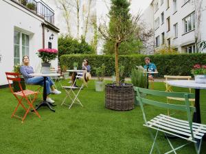 un gruppo di persone seduti ai tavoli in un giardino di Apartmenthaus Hamburg Les Jardins ad Amburgo