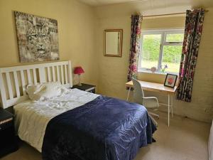 a bedroom with a bed and a desk and a window at English Farmhouse Cottage in Guildford