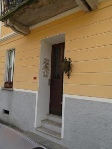 une maison jaune avec une porte marron et des escaliers dans l'établissement Casa Speranza PT, à Muralto