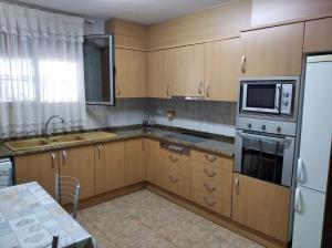 a kitchen with wooden cabinets and a microwave and a refrigerator at Marvel apartamento Vinaros in Vinaròs