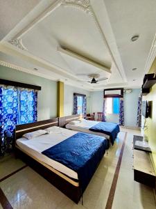 two beds in a bedroom with blue curtains at Bobby Premium Residency in Puri