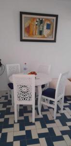 a white dining room table and chairs with a picture on the wall at Bel appartement au coeur du Port El Kantaoui in Port El Kantaoui
