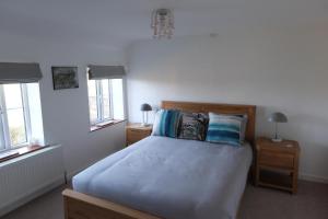 1 dormitorio con 1 cama grande con almohadas azules en Plain Street Cottage, en Port Isaac