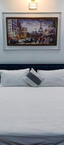 a bedroom with a white bed with a picture on the wall at Hillview 2BHK Flat in Dehradun in Dehradun