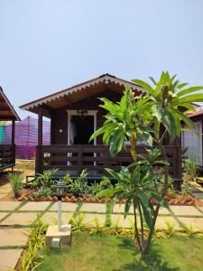 a house with a porch with palm trees in front of it at B R Cottages, 200 meters from Patnem Beach in Canacona +4 photos