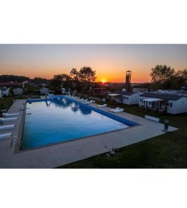 uma grande piscina com o pôr do sol ao fundo em bungalow jardim bonito 11zz em Pataias