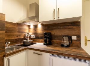 une cuisine avec des armoires blanches et des murs en bois dans l'établissement Familienfreundliche Stadt-Oase mit Arbeitsplatz - Bahnhofsnah, 2 Schlafzimmer, 76qm & gratis Kaffee- und Teeangebot, à Chemnitz